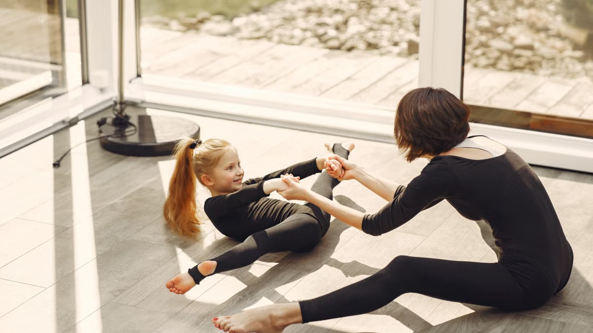 Mother and daughter bonding through indoor gymnastics and stretching exercises.