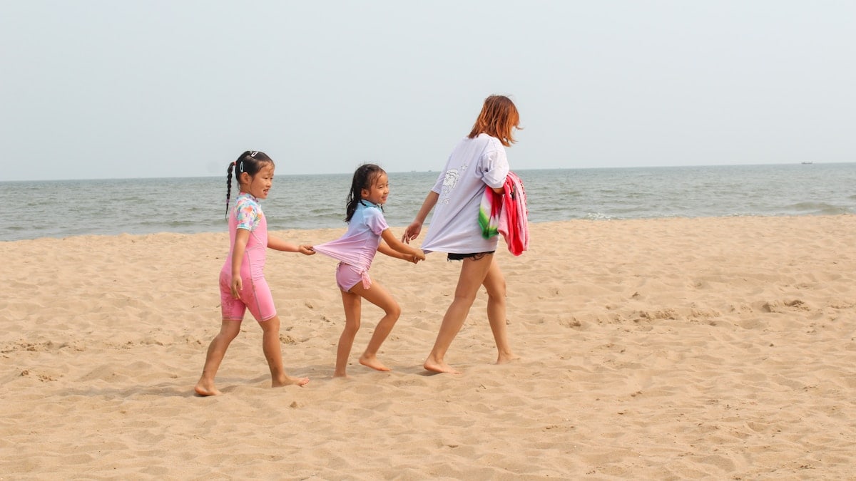 2 women walking on beach during daytime